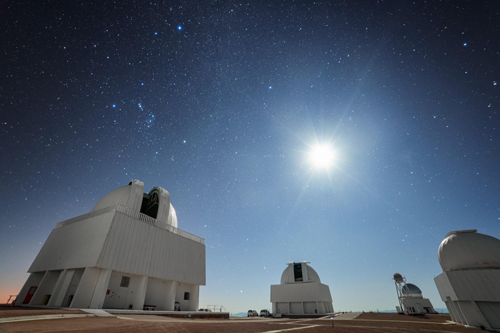 Moonlit observatory domes on a ridge under a sky full of stars
