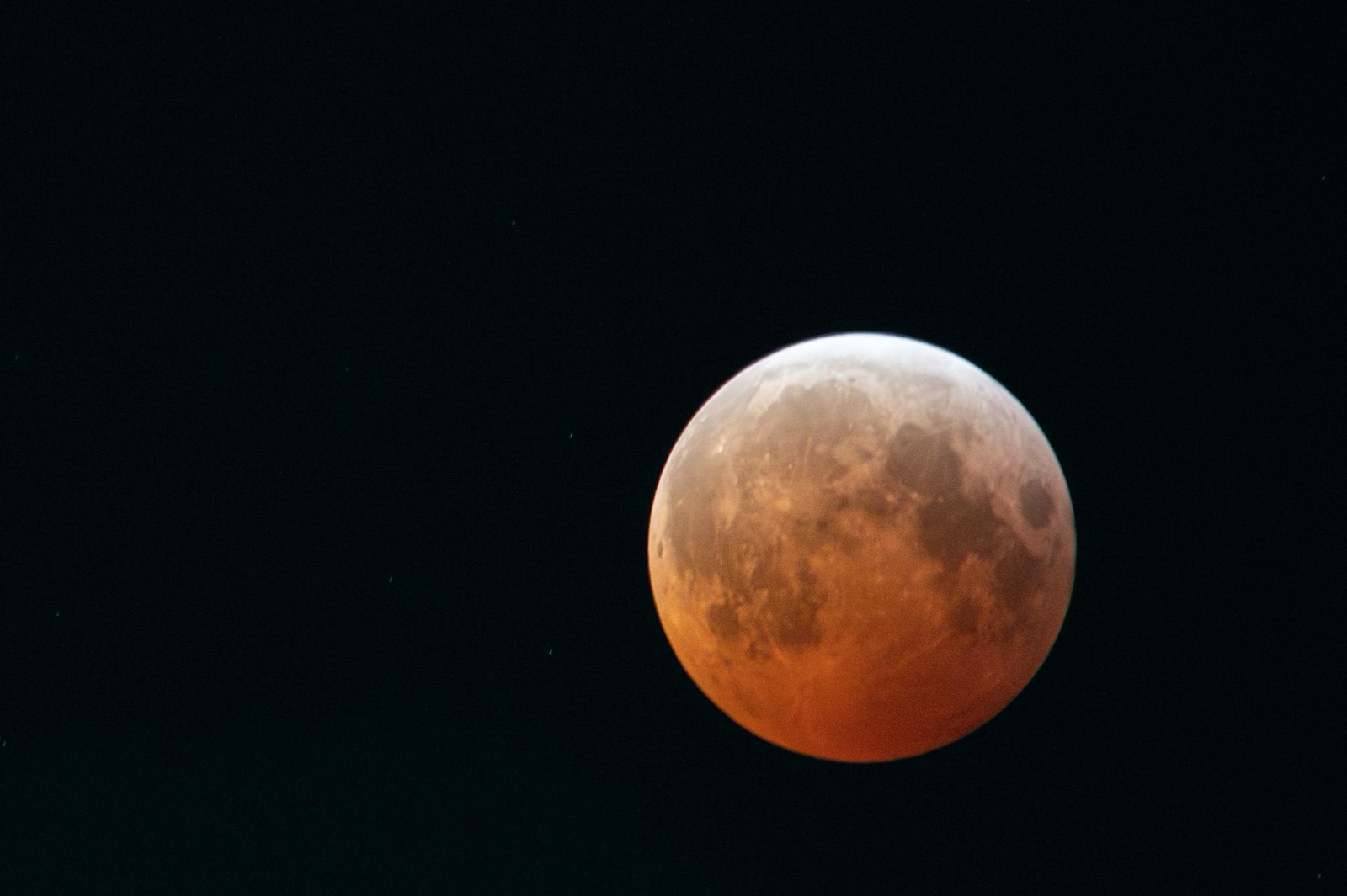 Copper-red fully eclipsed Moon against a black sky.