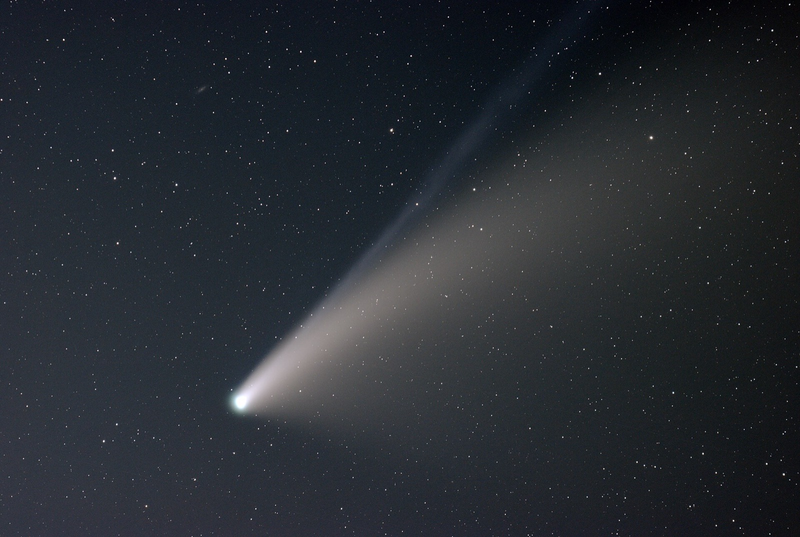 Comet with a long bright tail crossing a field of stars.