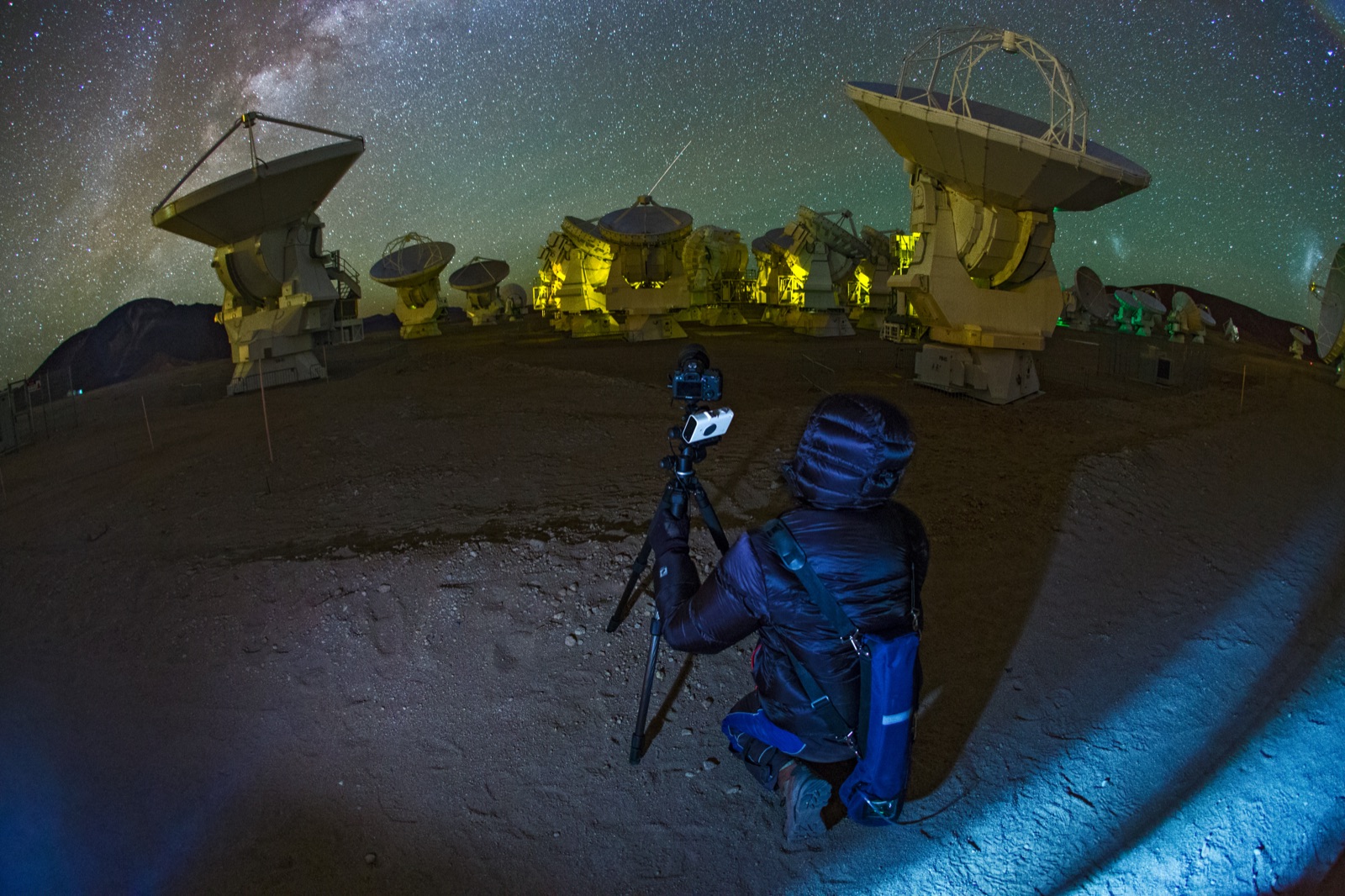 Camera on a small star tracker and tripod under the Milky Way beside radio telescope dishes